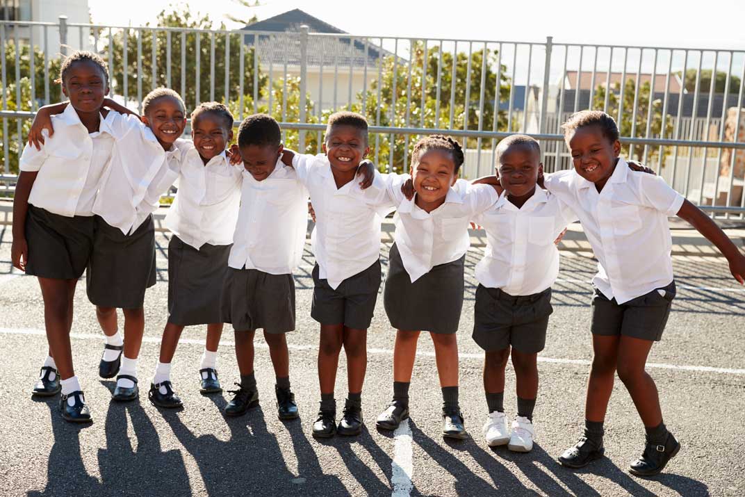 A row of smiling school learners in uniform with arms around each other in a Midrand schoolyard