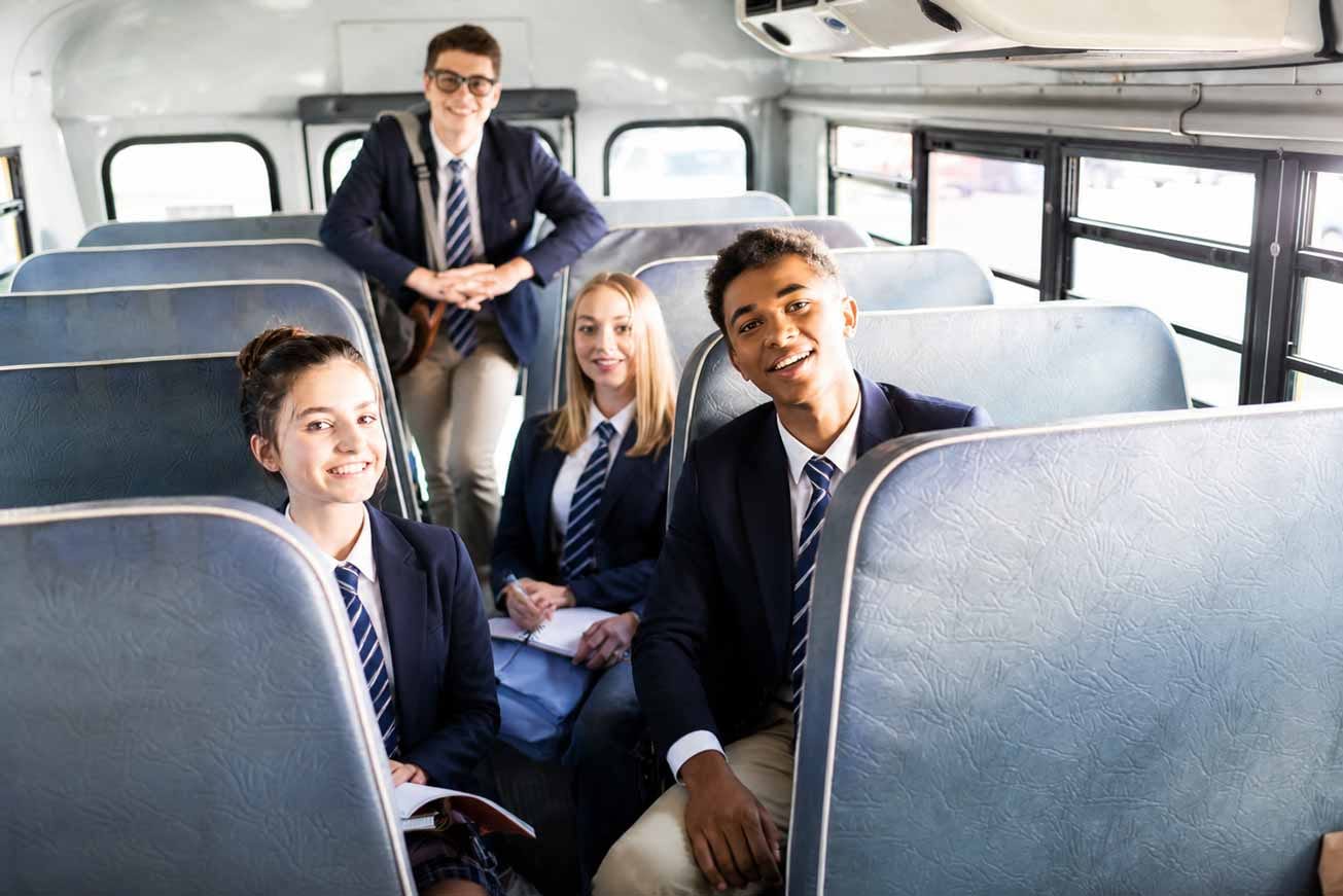Teenagers in school uniform smiling together on a Beremi scholar bus