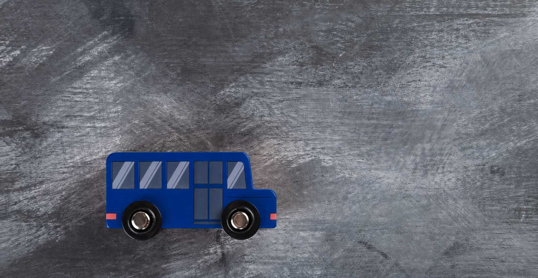 A navy wooden toy bus on a slate surface